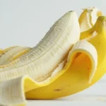 Banana peels stacked on a wooden surface, showcasing their natural texture and vibrant yellow color.