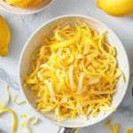 Fresh lemon peels arranged on a cutting board, showing their vibrant yellow color and textured surface